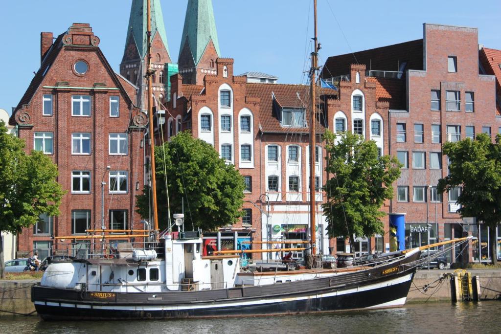 un bateau assis dans l'eau devant les bâtiments dans l'établissement Apartment Traveblick, à Lübeck
