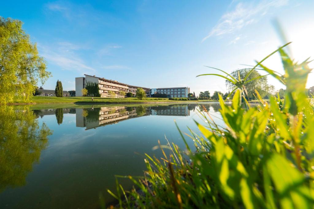 a view of a lake with buildings in the background at Hotel Mas Solà in Santa Coloma de Farners