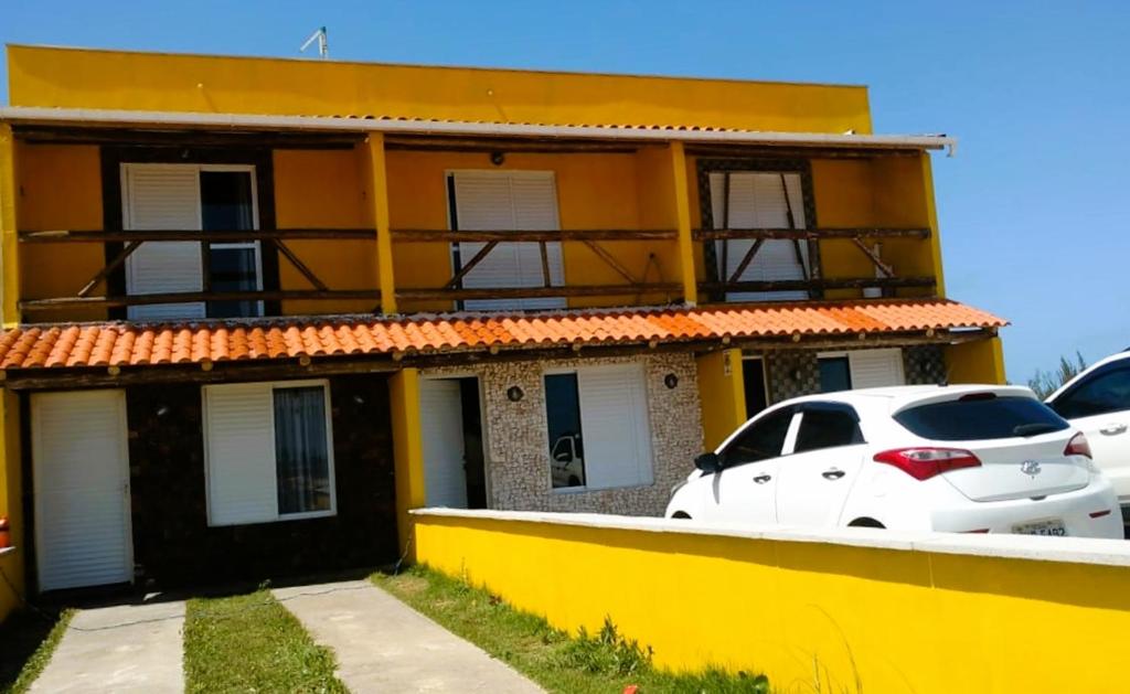 a yellow house with cars parked in front of it at Recanto das Pedras - Casa Pedra Ferrugem Com vista para o mar in Jaguaruna