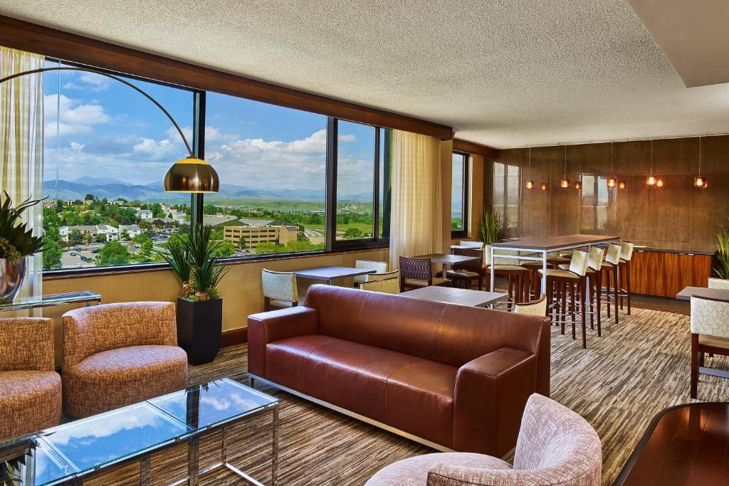 a living room with a couch and chairs and a large window at Sheraton Denver West Hotel in Lakewood