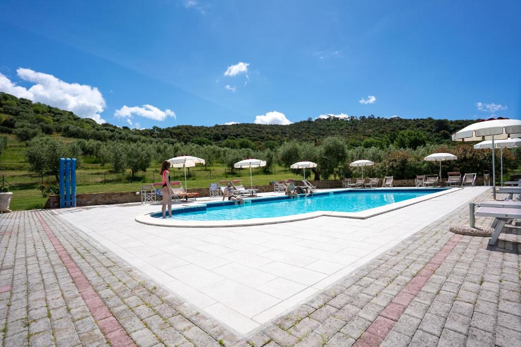 a woman standing in front of a swimming pool at Agriturismo La Banchella in Scarlino