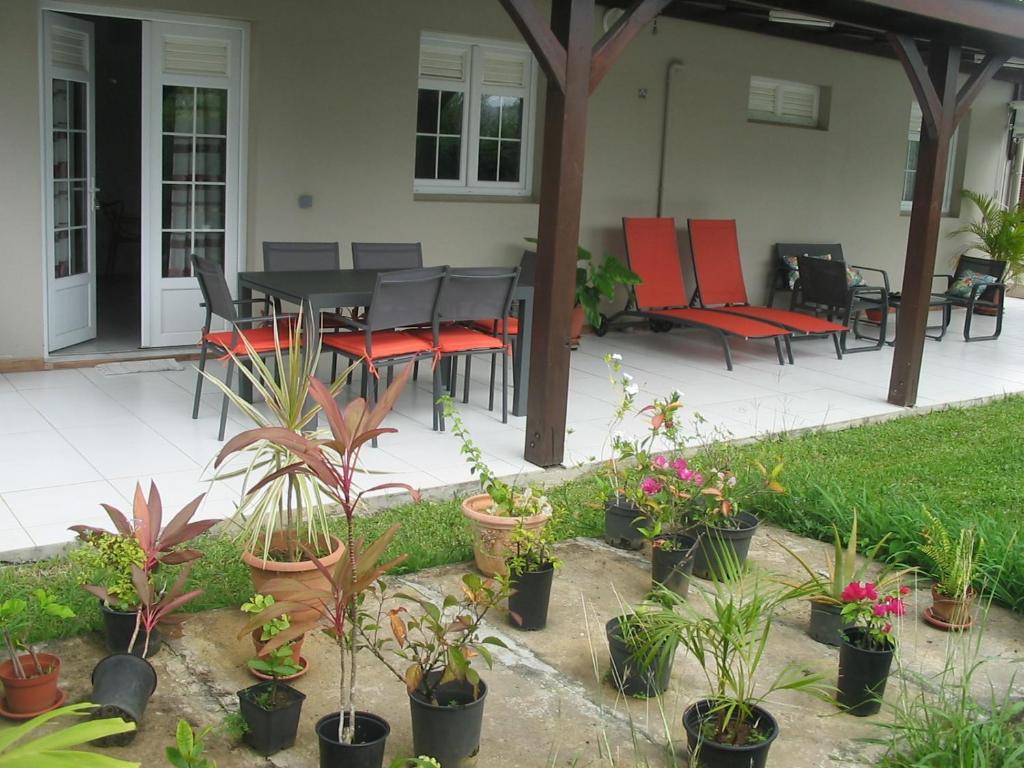 a patio with a table and chairs and potted plants at PETIT PARADIS in Quartier Morne la Valeur