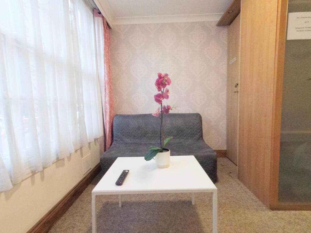 um quarto com um sofá e uma mesa com uma flor em Flat 1 at 6 Taunton Mews em Londres