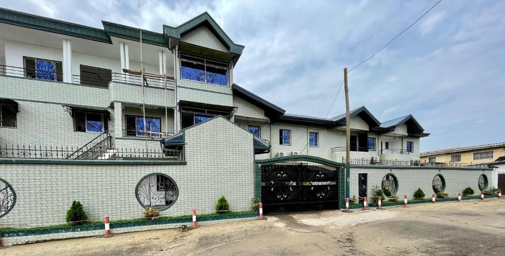 ein großes weißes Gebäude mit großer Garage in der Unterkunft Résidence 2JGE in Douala