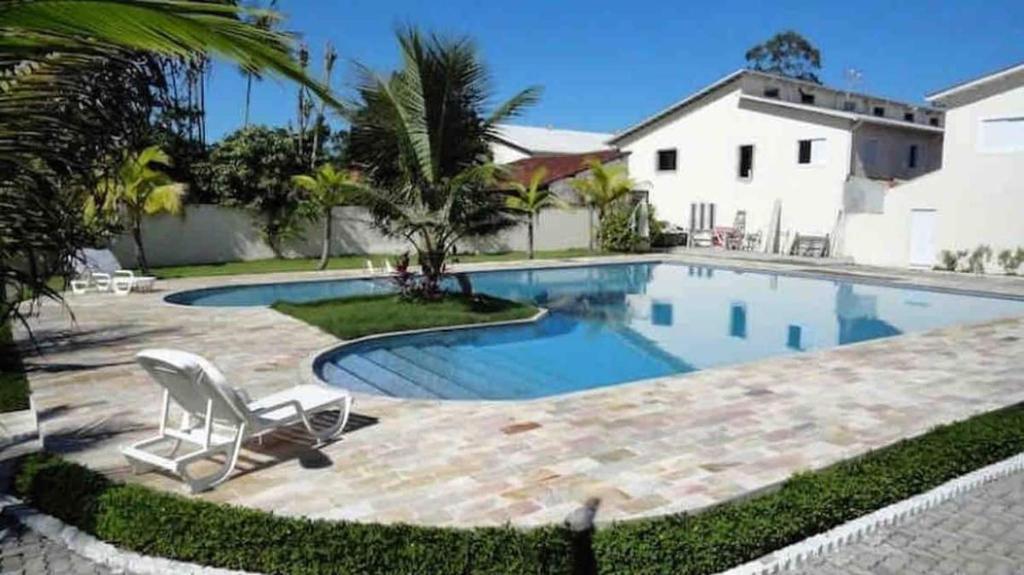 una piscina con una silla junto a una casa en Casa de praia em condomínio fechado Juquei, en São Sebastião