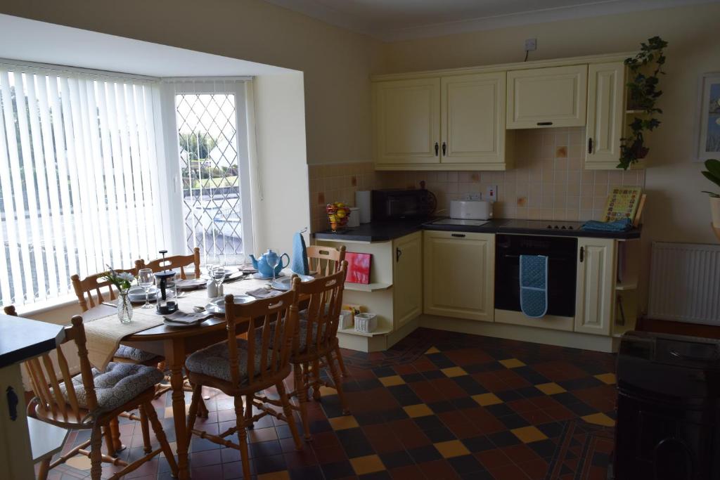 a kitchen with a table and chairs and a kitchen with white cabinets at Teach Kitty Con in Dungloe