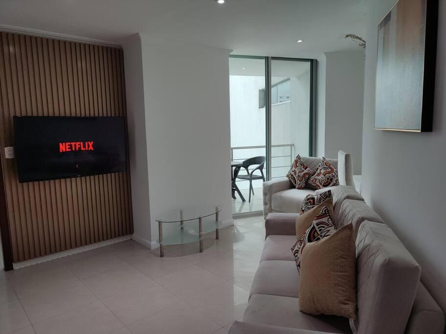 Suite exclusiva con balcón y maravillosa vista في غواياكيل: غرفة معيشة مع كنبتين وتلفزيون