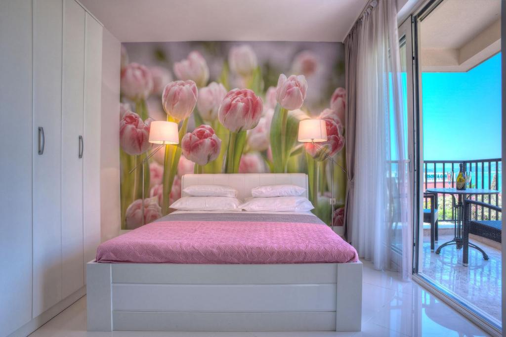 1 dormitorio con 1 cama con sábanas rosas y flores rosas en Guest House Pržno Bay, en Sveti Stefan