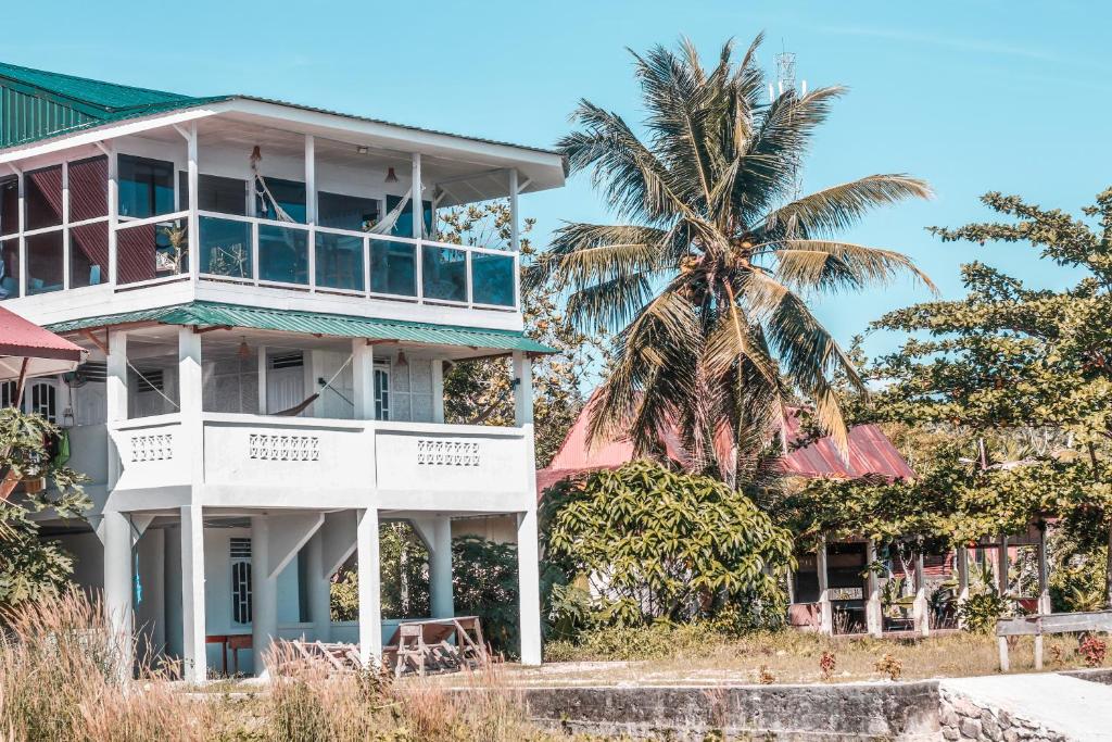 a white building with a palm tree in the background at Nias Surf Stay in Lagudri