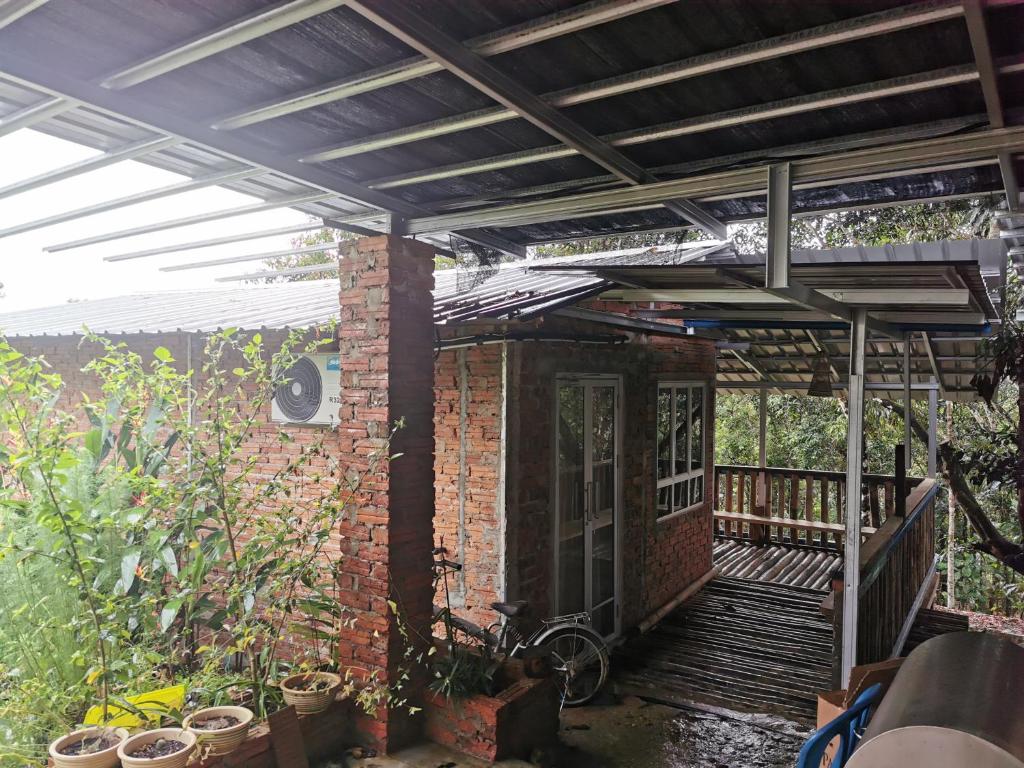 una casa de ladrillo con toldo y una bicicleta en un porche en Cassava Homestay - Rumah Santai, en Kampong Lamanak