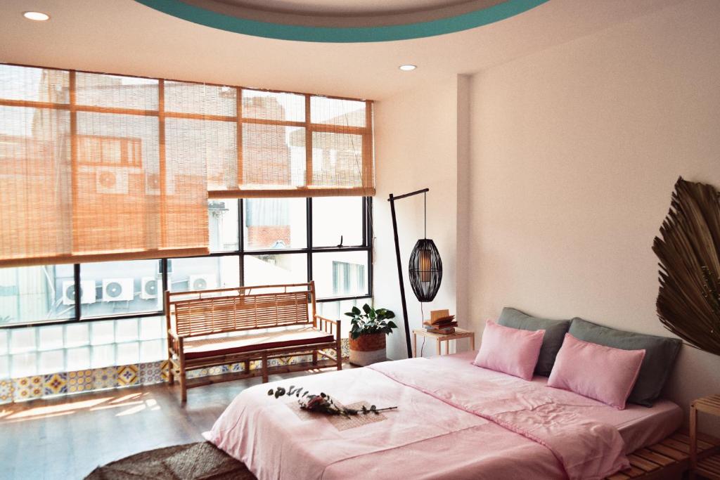 a bedroom with a bed with pink sheets and a bench at Coucou Homestead I - Homestay & Dorm District 1 in Ho Chi Minh City