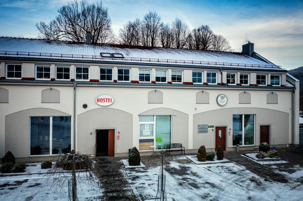 Un grand bâtiment blanc avec de la neige au sol dans l'établissement Hostel Browar Jedlinka, à Jedlina-Zdrój