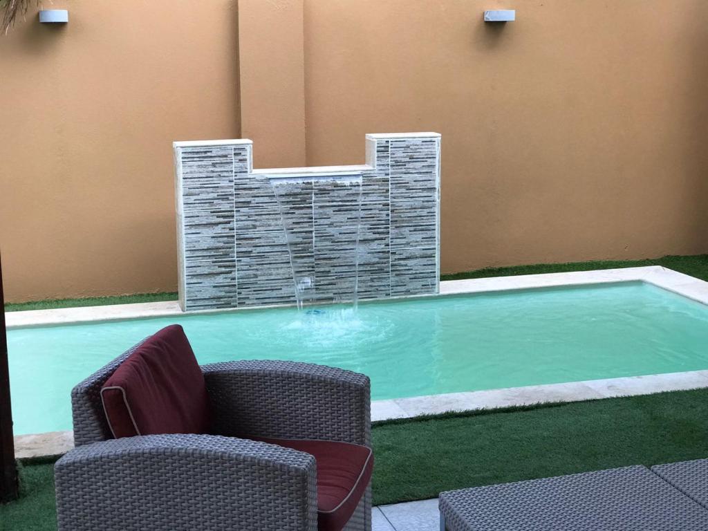 - une piscine avec 2 chaises et une fontaine dans l'établissement LUXURIOUS 3 BEDROOM HOUSE IN GOLD COAST, à Palm-Eagle Beach