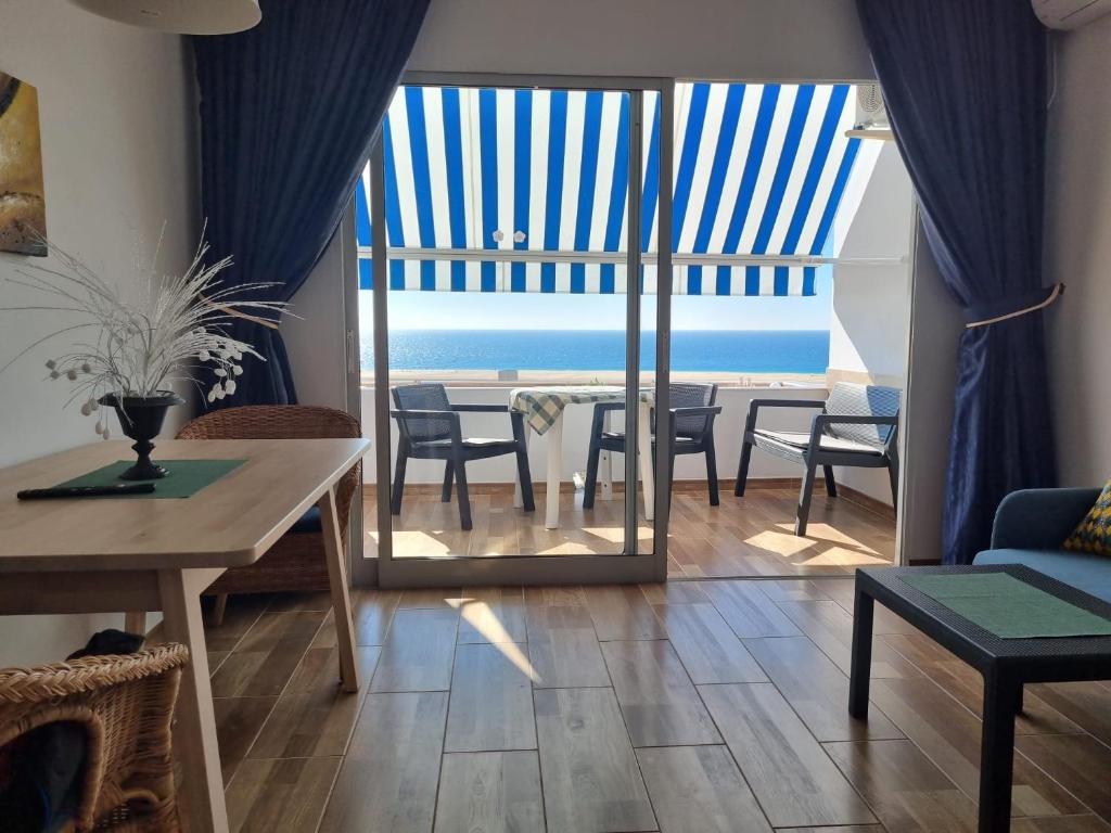 Sala de estar con mesa y vistas al océano en apartamentos Vv casafaromar, en Morro del Jable