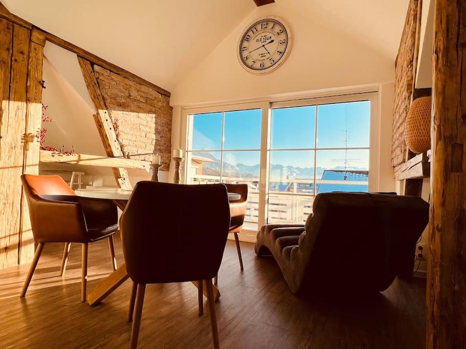 - un salon avec une horloge, une table et des chaises dans l'établissement Penthouse im Dachgeschoss, à Sonthofen