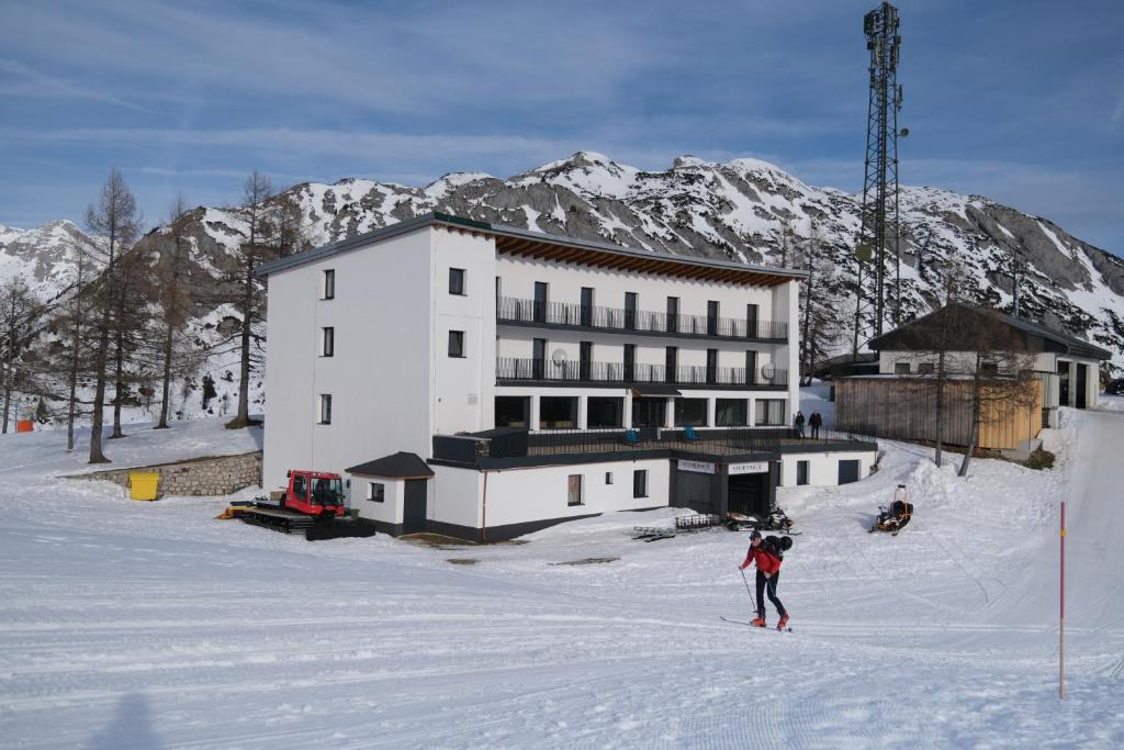 eine Person auf Skiern im Schnee vor einem Gebäude in der Unterkunft Alpenhotel Steirerhof in Tauplitzalm
