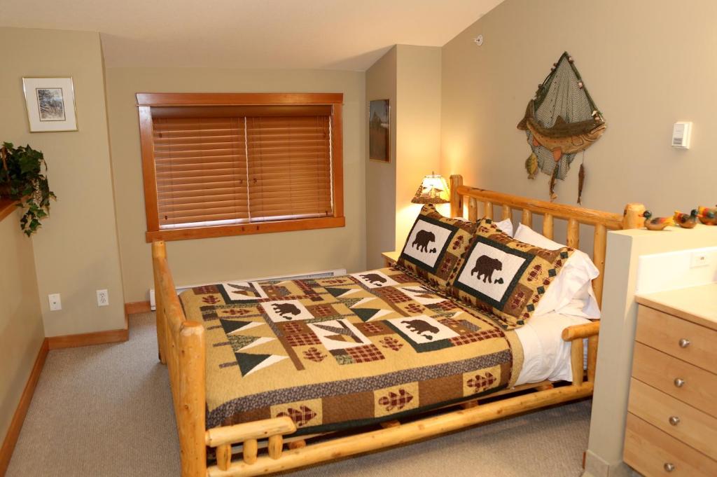 een slaapkamer met een bed met een houten frame bij Apartment 405 Bear Creek Crossing in Canmore