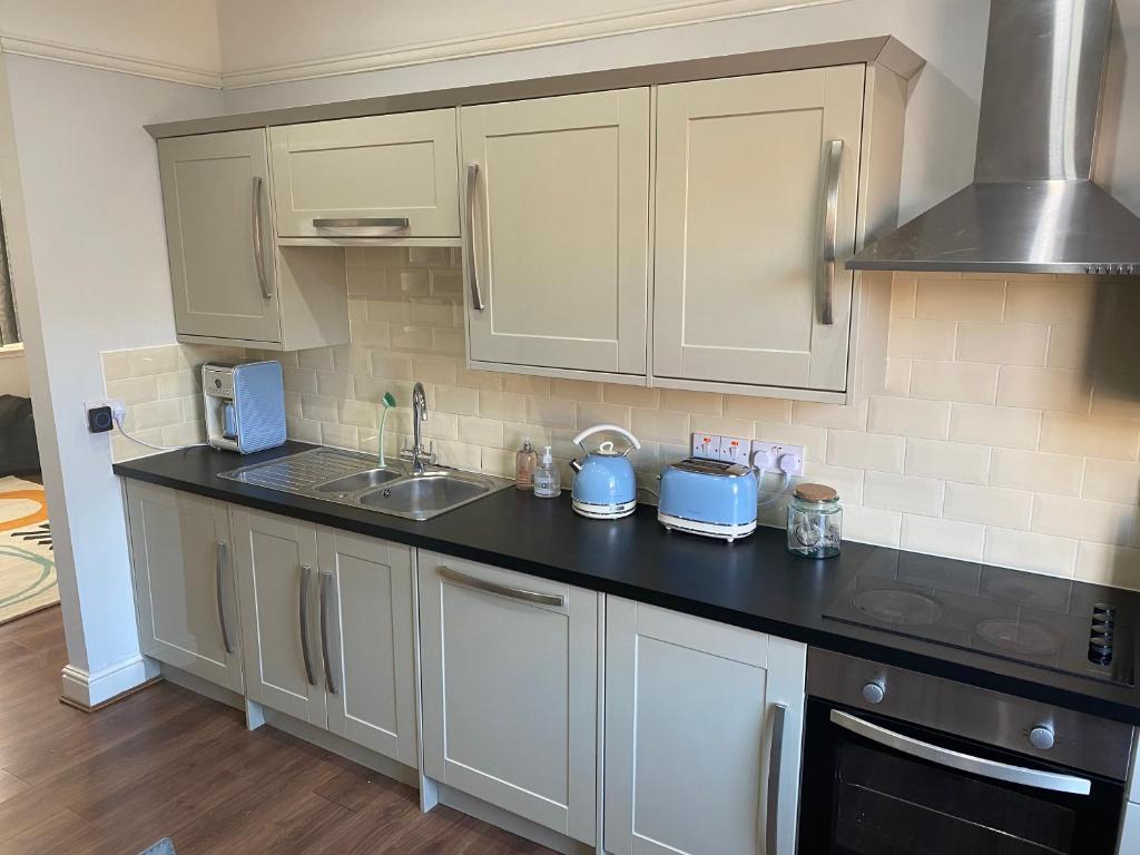 a kitchen with white cabinets and a black counter top at Invicta Apartment in Ashford