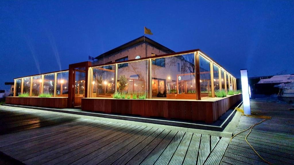 une grande maison en verre avec des plantes la nuit dans l'établissement NEPTUNUS, à Nieuport