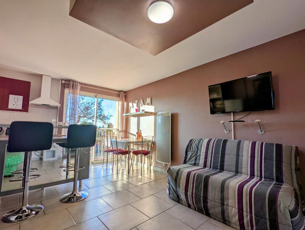un soggiorno con un divano e una TV a parete di Appartement cosy avec parking proche port et plage a Cap d'Agde