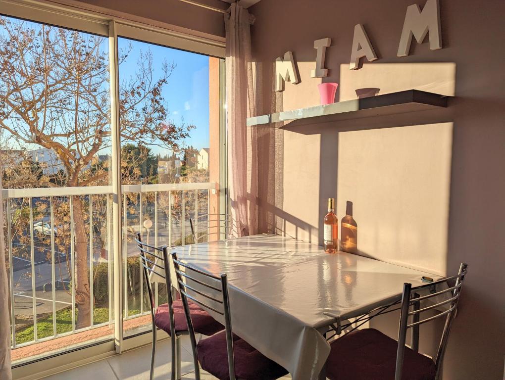 a dining room with a table and chairs and a window at Appartement cosy avec parking proche port et plage in Cap d&#39;Agde