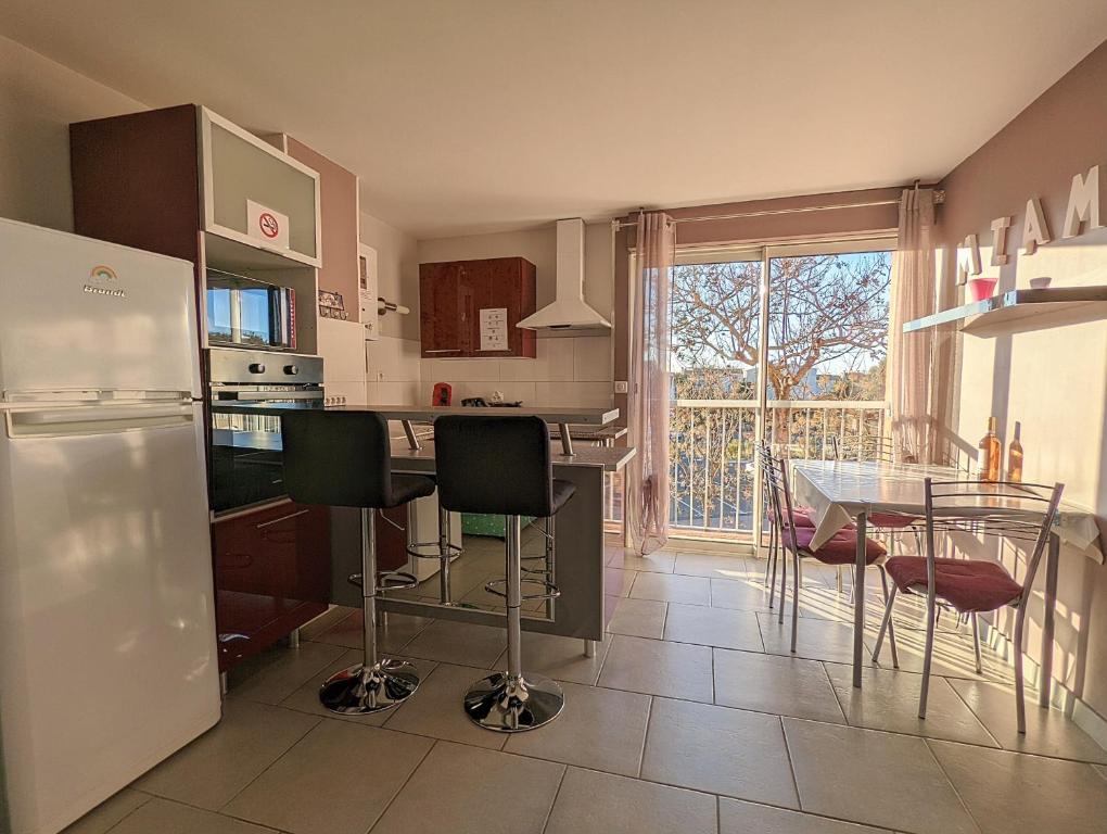 a kitchen with a counter and a table with chairs at Appartement cosy avec parking proche port et plage in Cap d&#39;Agde