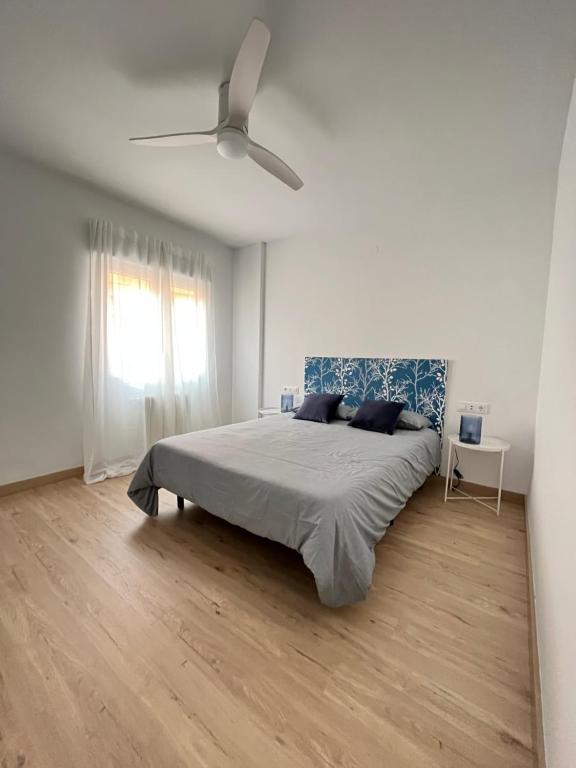 a white bedroom with a bed and a ceiling fan at MGG - Apartamento Muelle in Albacete