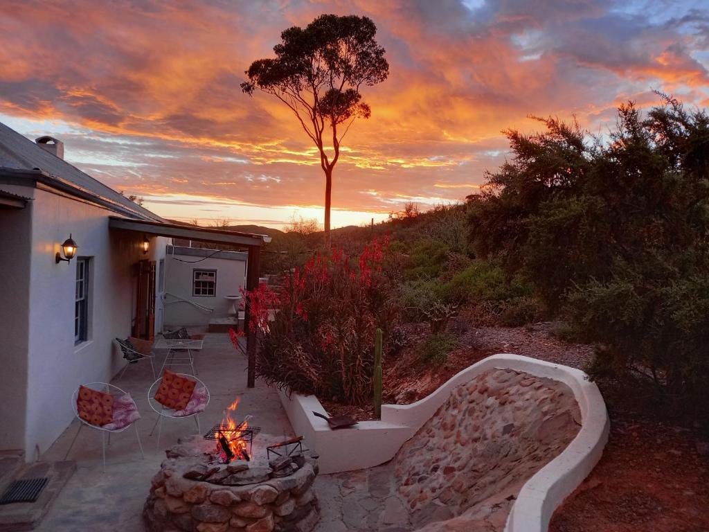 a backyard with a fire pit and a tree at Wolverfontein Karoo Cottages in Ladismith