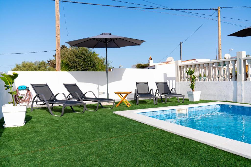 a backyard with a pool and chairs and an umbrella at VILLA XOROI in Cala en Porter