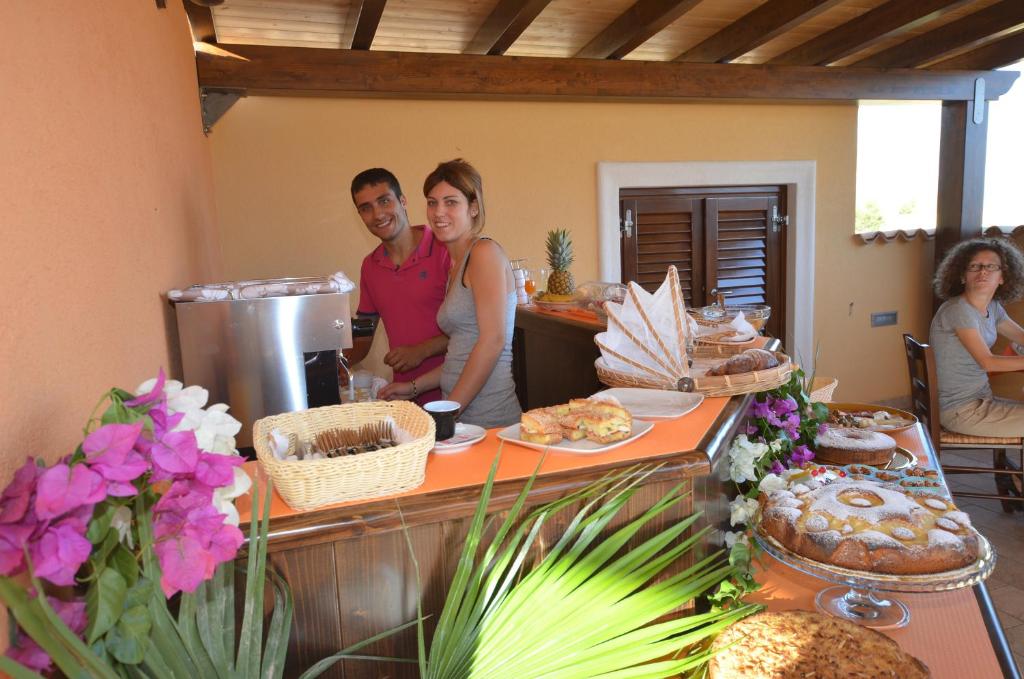 een groep mensen die rond een tafel met eten staan bij Baia Santa Margherita B&B in Castelluzzo