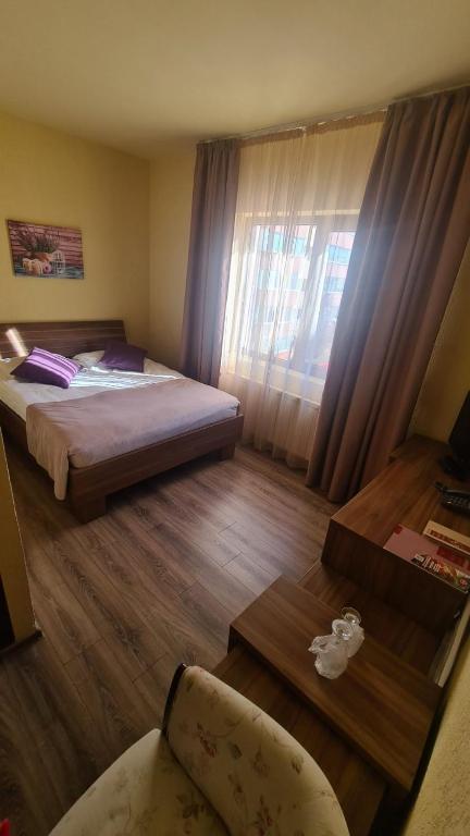 a bedroom with a bed and a table and a chair at Hotel Gema in Braşov