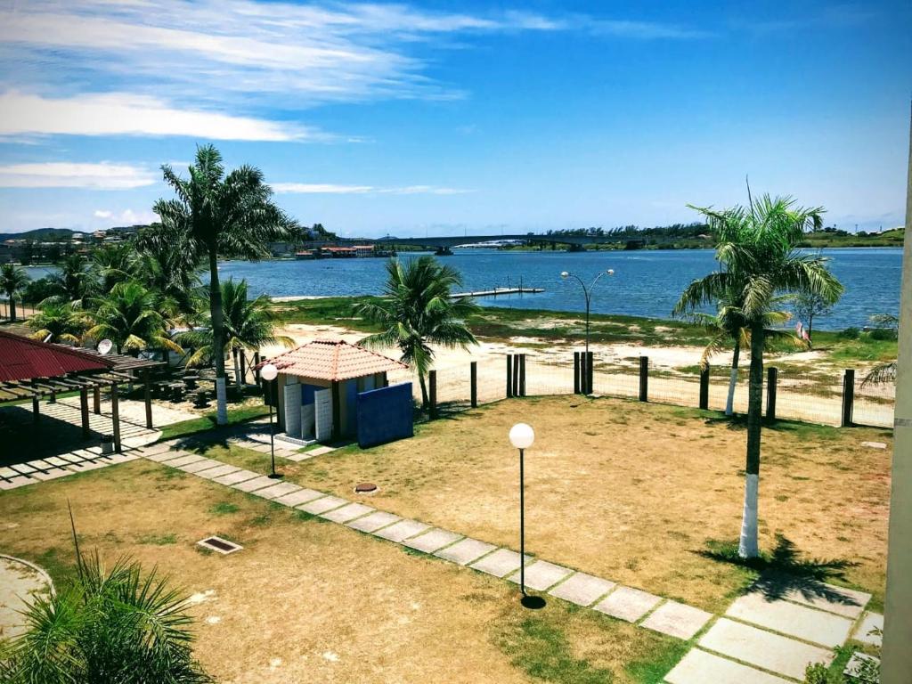 vistas a una playa con palmeras y agua en Apartamento Marina Clube Vista Lagoa, en Cabo Frío