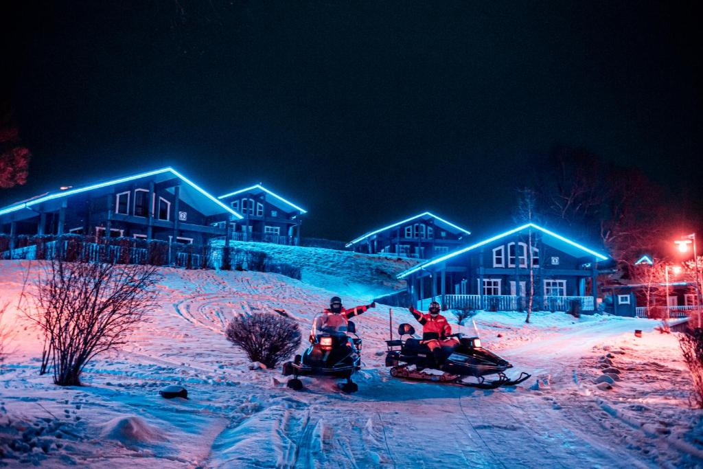 dos personas montando en motos de nieve en la nieve por la noche en Эко-клуб Голицыно, en Mikhaylovka