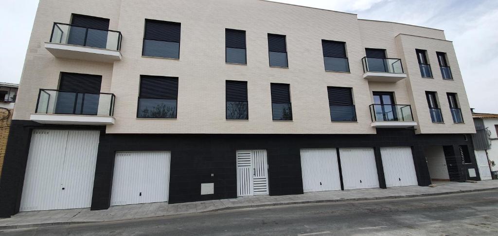 un edificio con cuatro puertas blancas de garaje en una calle en JOSE APARTAMENTo, en San José de La Rinconada