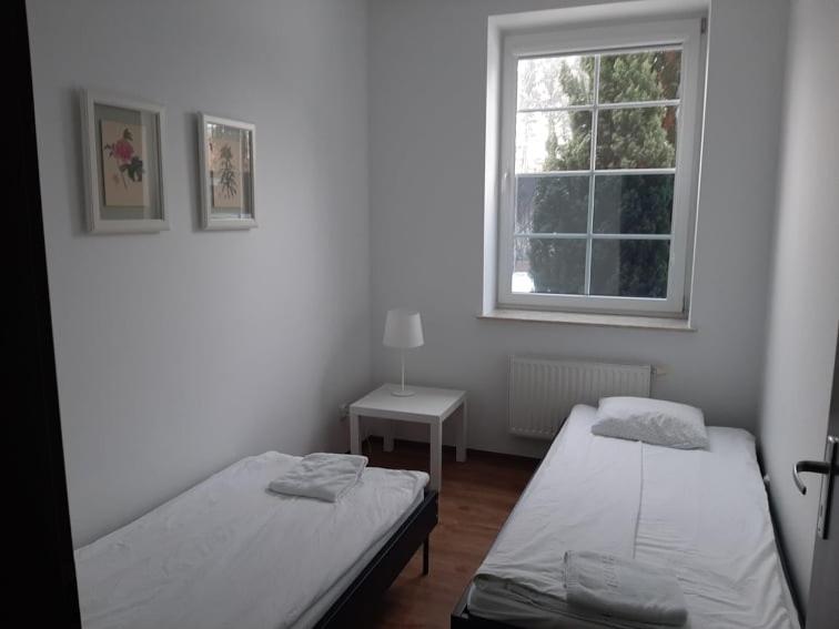 a white room with two beds and a window at Apartament żeglarski Węgorzewo in Węgorzewo