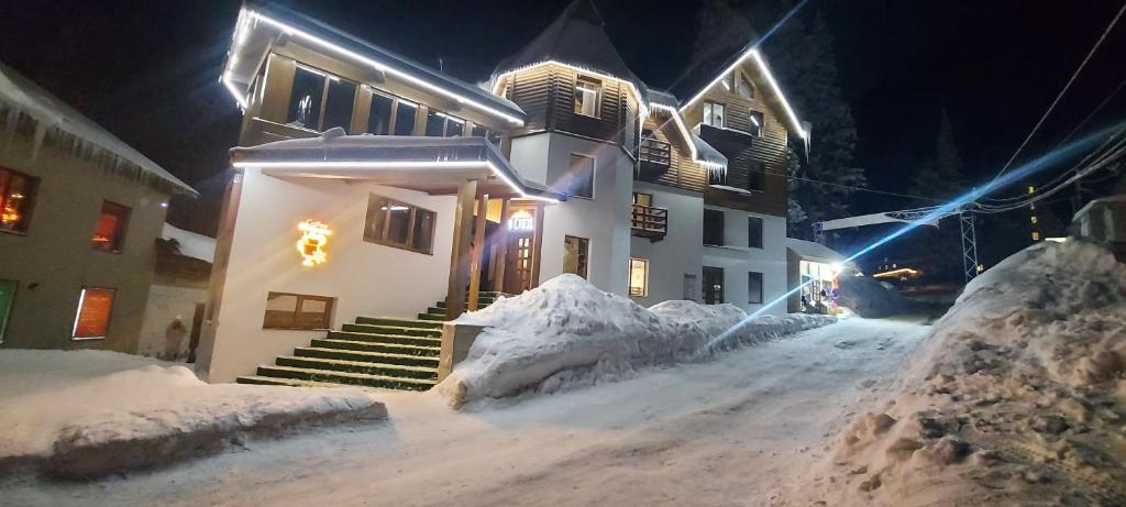a house is covered in snow at night at U Stozi Hotel in Dragobrat
