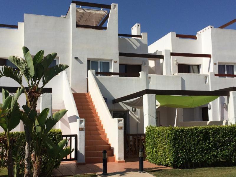 a large white house with stairs and a green umbrella at Casa belgica in Alhama de Murcia