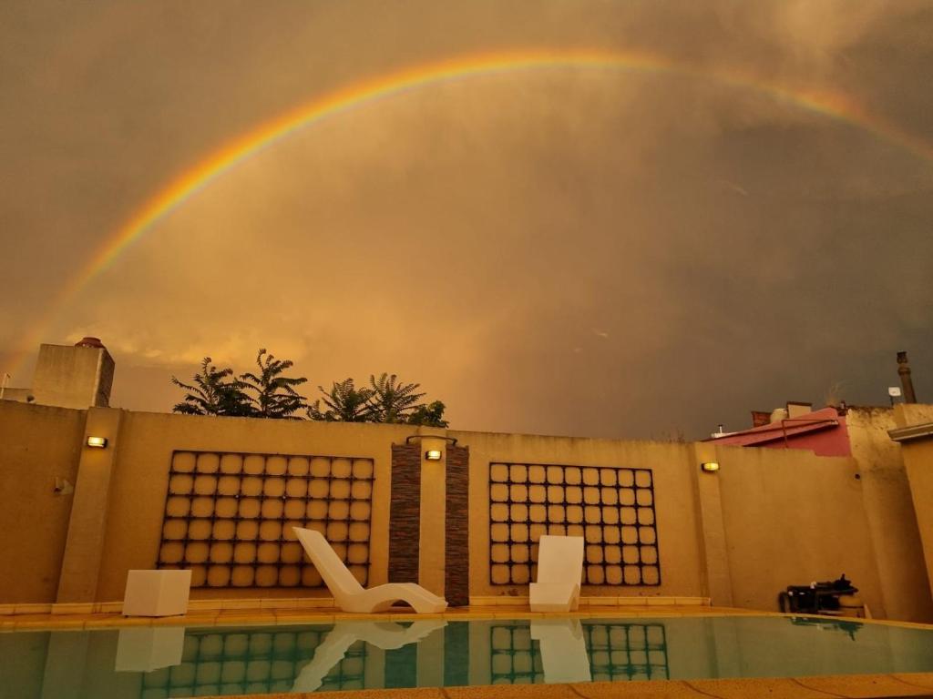 a rainbow over a house with a swimming pool at DON Hotel CHIVILCOY in Chivilcoy
