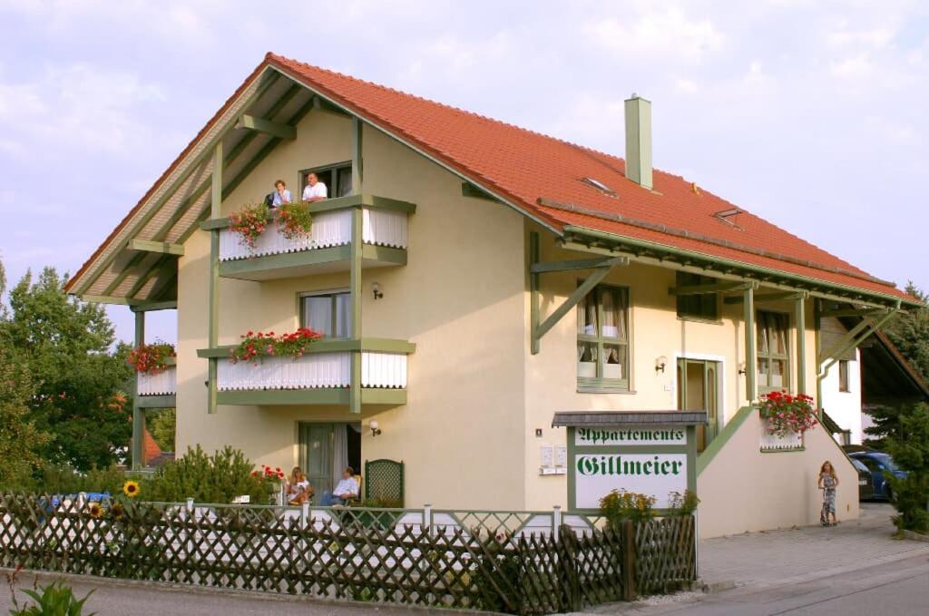 uma casa com telhado vermelho e pessoas em varandas em Appartements Gillmeier Herta em Bad Griesbach