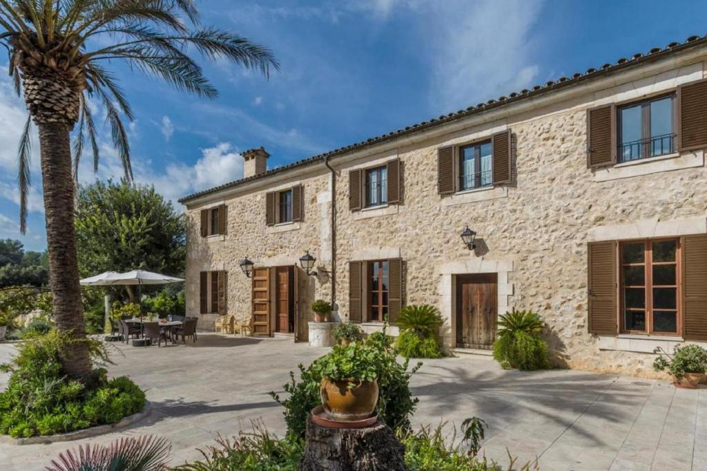 a stone house with a palm tree in front of it at Cadell Gran in Sa Pobla