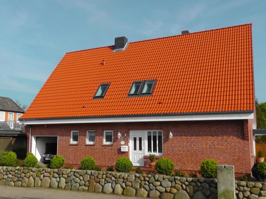 ein rotes Backsteinhaus mit orangefarbenem Dach in der Unterkunft Haus Wattenmeer in Tönning