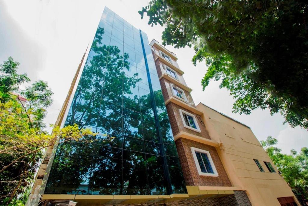 a glass building with a reflection of trees on it at Hotel Gulshan Lake View in Dhaka