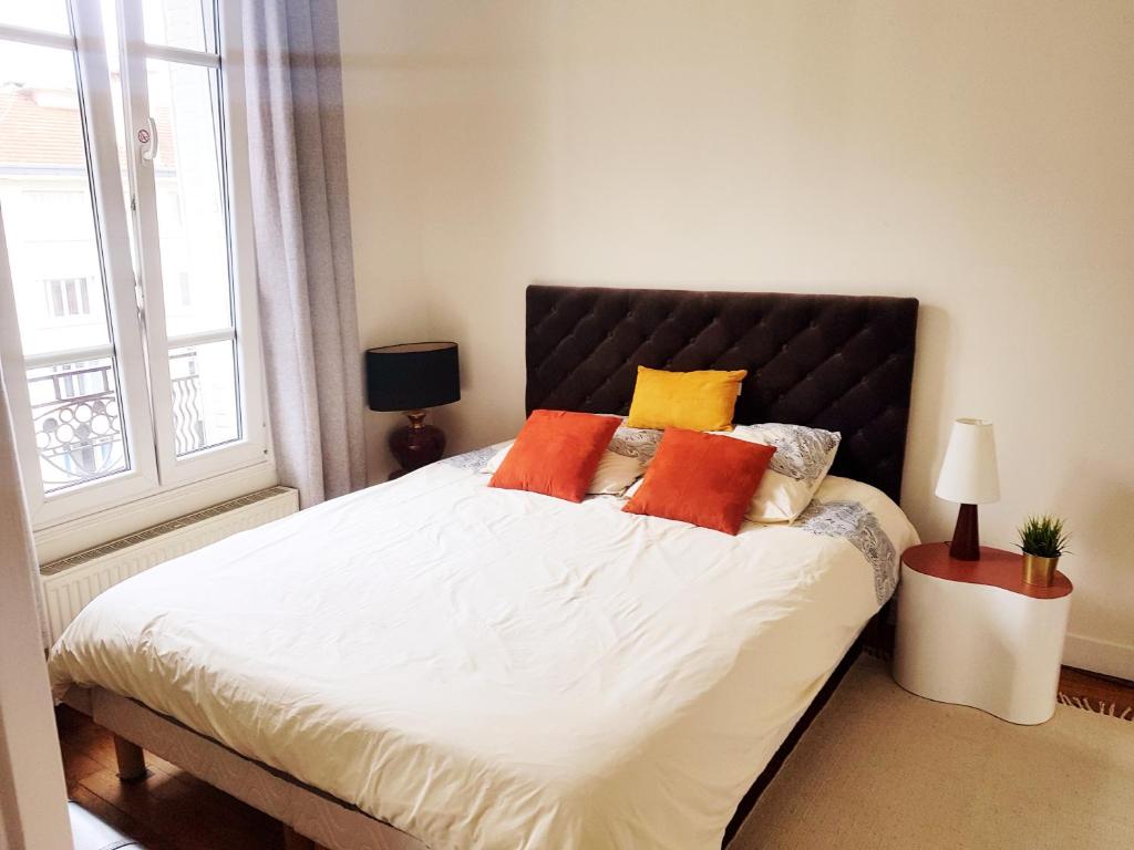 1 dormitorio con 1 cama grande con almohadas de color naranja y amarillo en Anna's Home Sweet Home en Boulogne-Billancourt