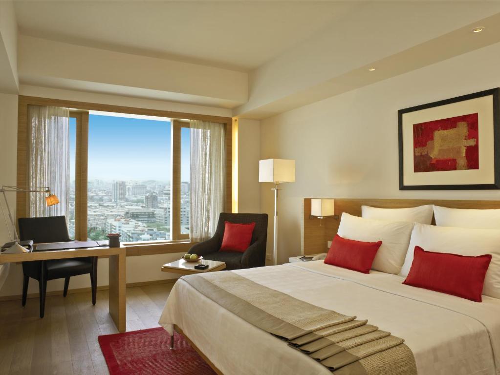 a hotel room with a bed and a desk and a window at Trident Nariman Point in Mumbai