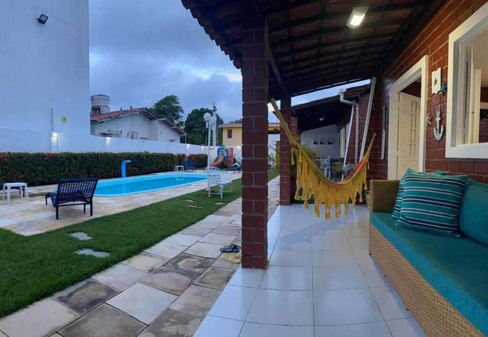 a patio with a couch next to a pool at Casa em Tamandaré-Carneiros CondFechado a 100m do mar in Tamandaré