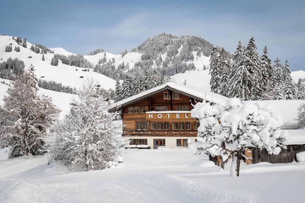 eine Blockhütte im Schnee mit schneebedeckten Bäumen in der Unterkunft Le Petit Relais in Gstaad