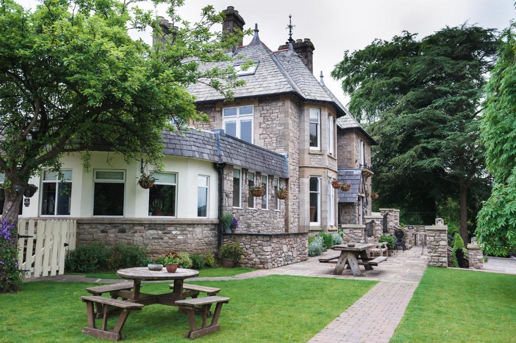 a house with picnic tables in front of it at Romneys Apartments & Suites in Kendal