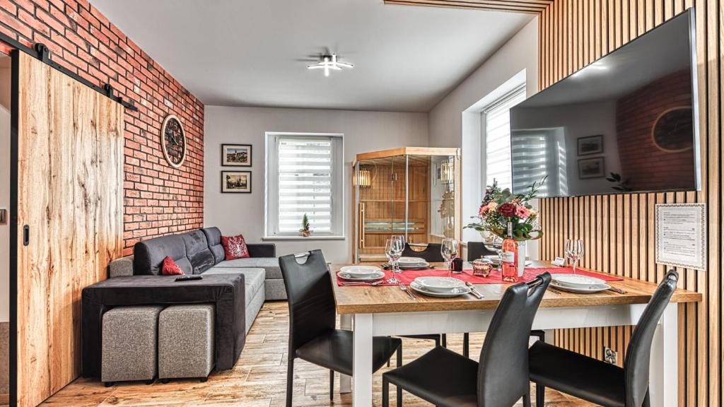 a dining room and living room with a table and chairs at Apartament w Starym Tartaku 1 z Sauną - 5D Apartamenty in Świeradów-Zdrój