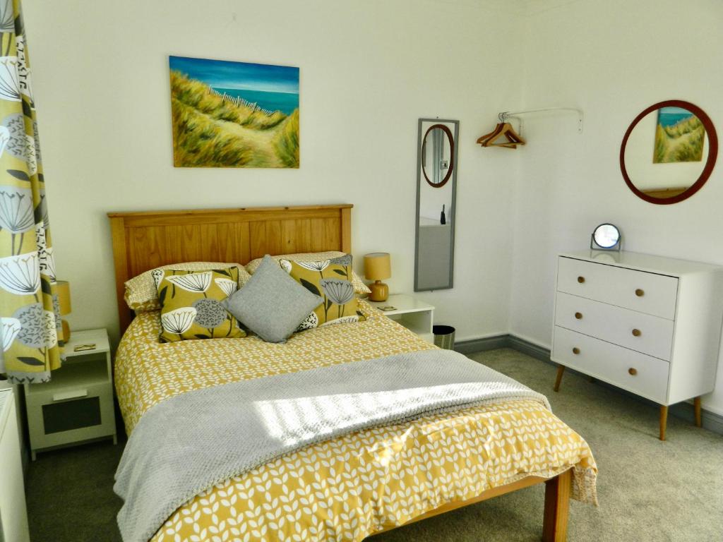 Schlafzimmer mit einem Bett, einer Kommode und einem Spiegel in der Unterkunft 'Harbour View' on the river by Gorleston's award winning beach - Pet free! in Gorleston-on-Sea