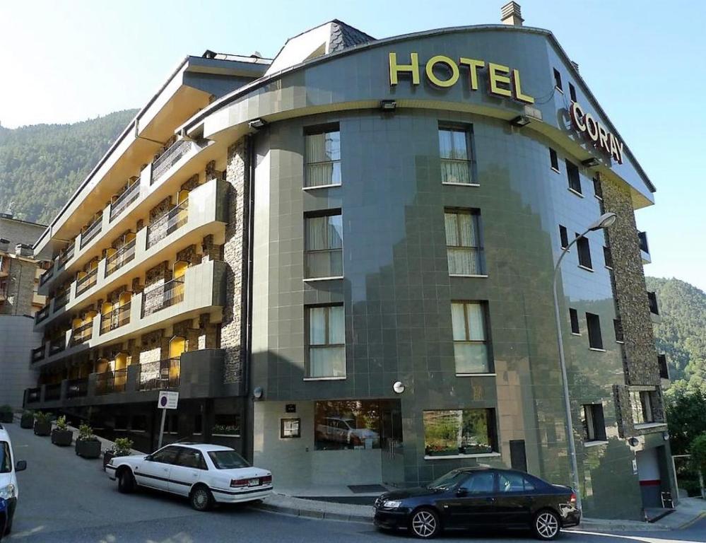 un hotel con dos coches estacionados frente a él en Hotel Coray, en Encamp